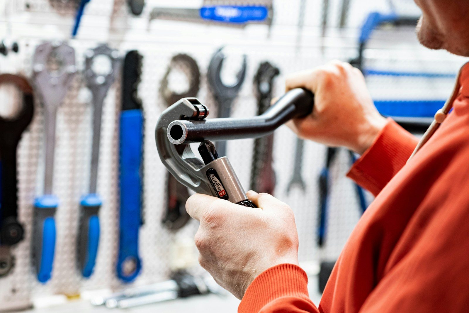 a man holding a wrench in front of a wall of tools
