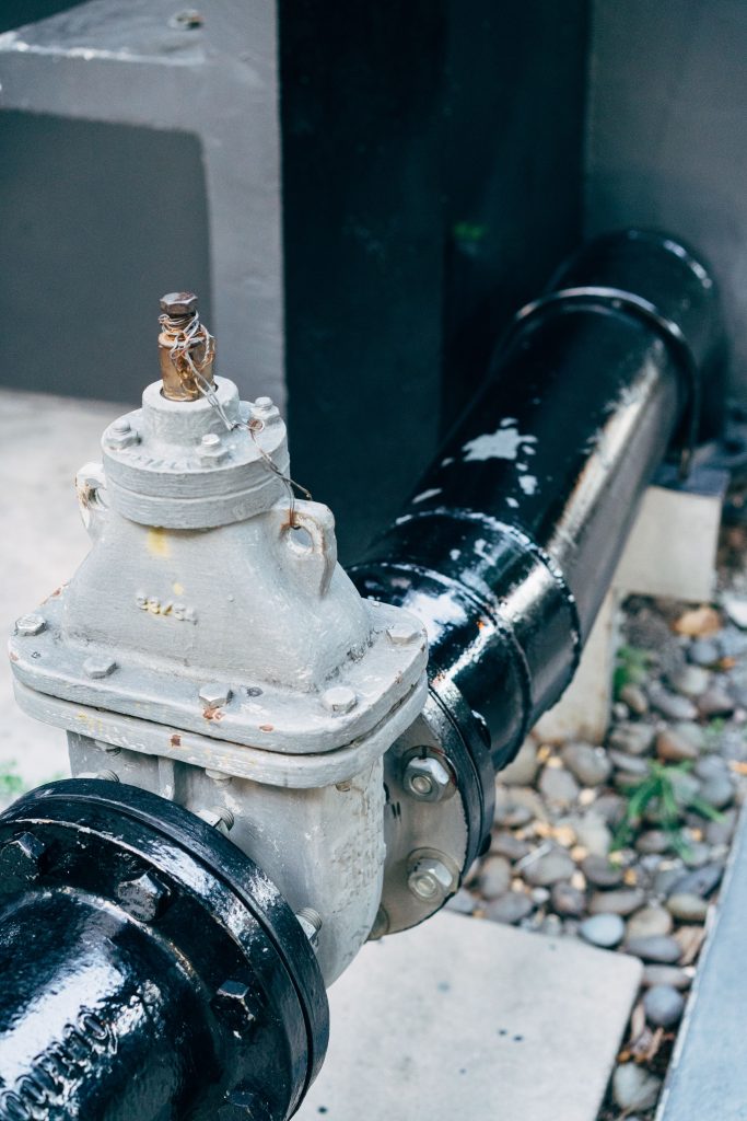 Detailed view of a plumbing valve with connected black pipeline, essential for industrial applications.